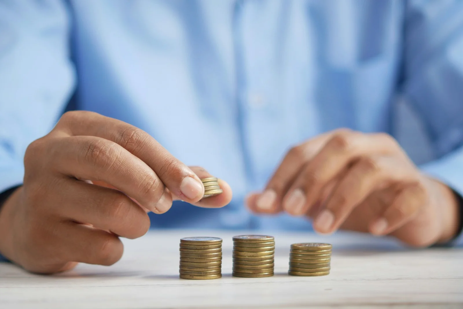 Hands stacking coins on a clean surface, representing wealth-building with Novae Money